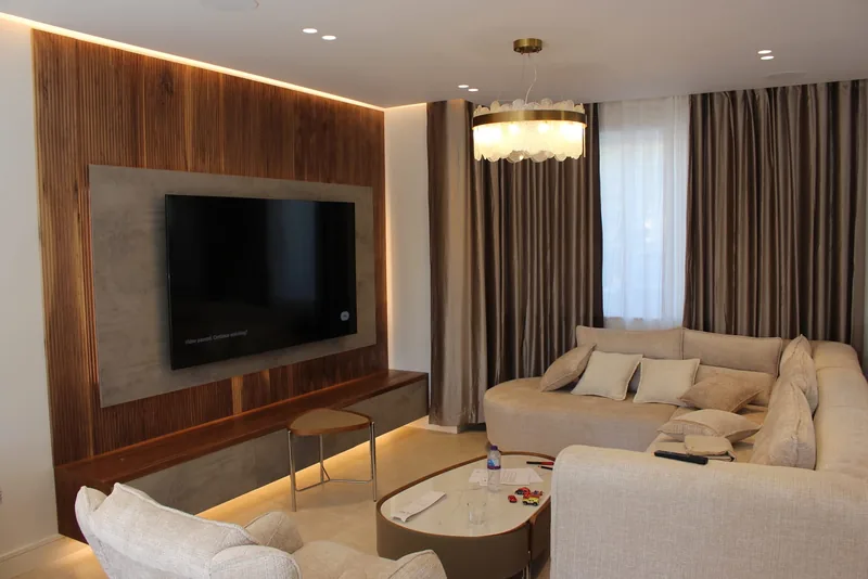 Lounge: Walnut panelled media wall with LED cove lighting, downlights and a statement pendant