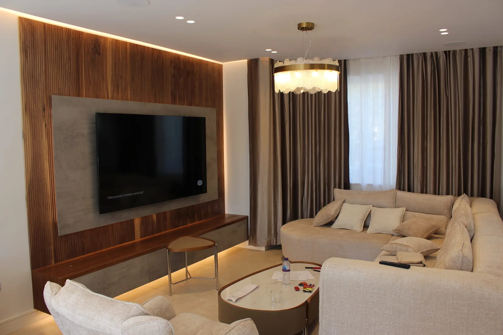 Lounge with a walnut panelled media wall, LED cove lighting and downlights, wired by E.A Electrician