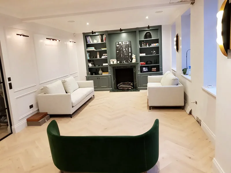 Panelled living room with picture lights, downlights and lit shelving either side of the fireplace