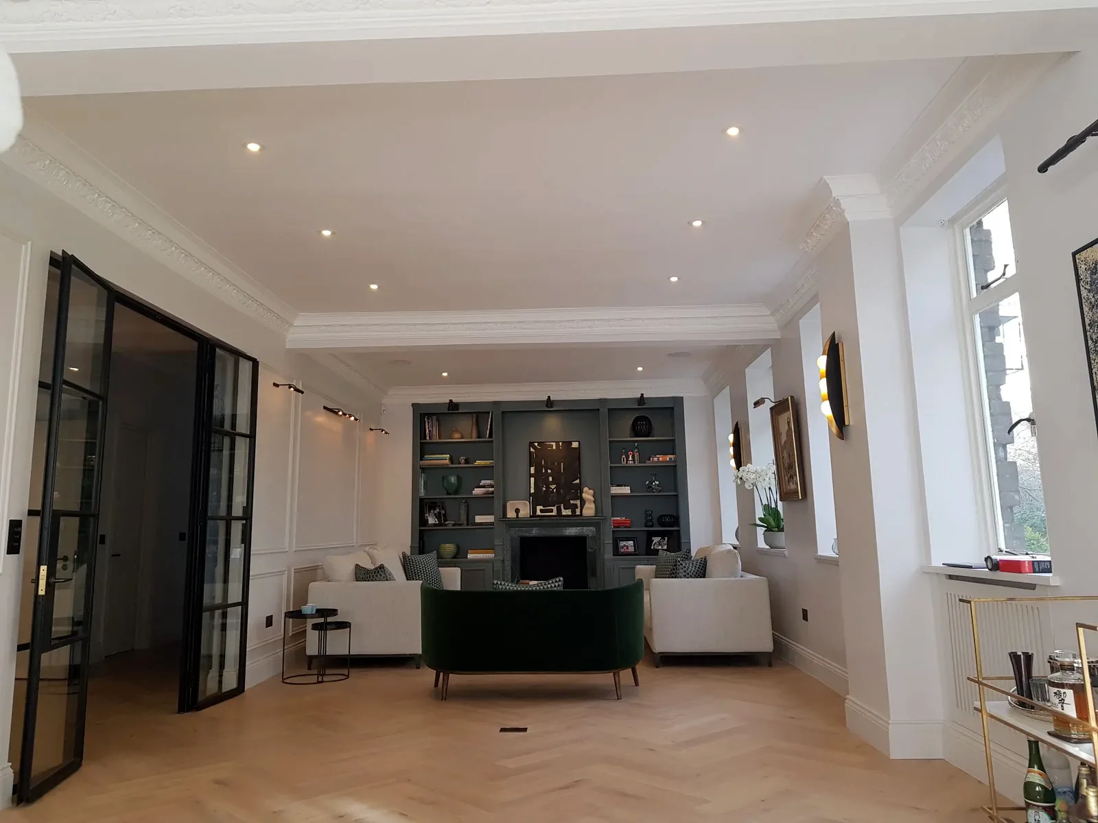 Renovated open-plan living room with downlights and a lit display wall